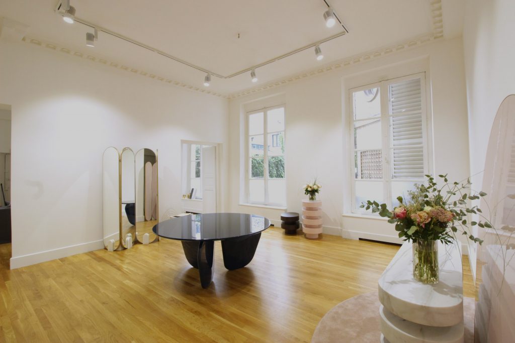 Showroom épuré au 47 Rue des Tournelles, avec sol en bois, murs blancs et lumière naturelle venant des grandes fenêtres.