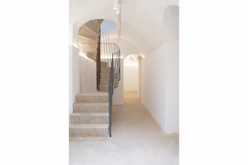 Escalier spacieux et lumineux dans l’espace à louer au 5 Rue Payenne, Paris, avec des murs blancs et un sol beige.
