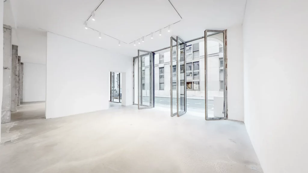 projecteur orienté vers un produit exposé sur socle, dans une galerie aux murs blancs du Marais